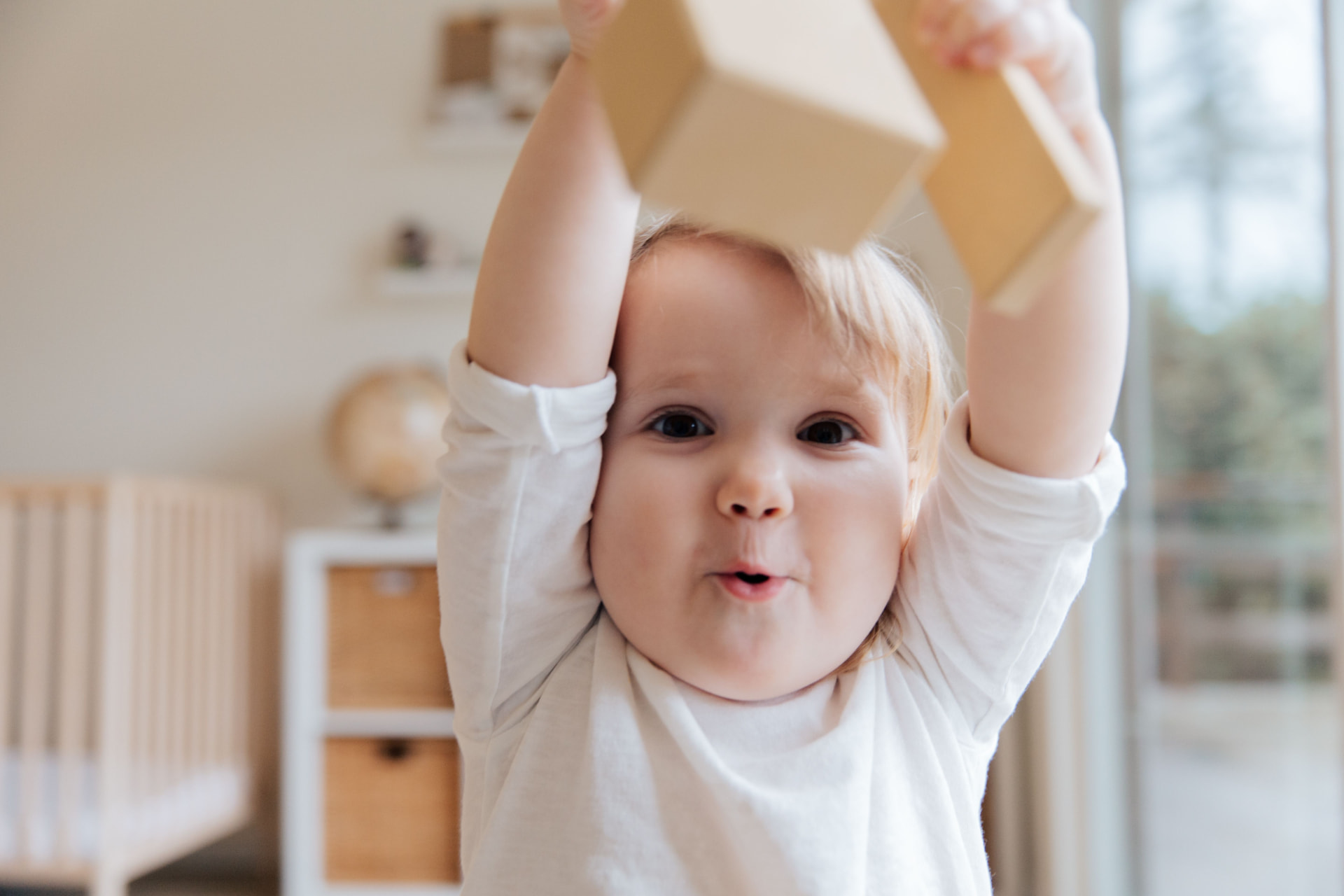 A smiling toddler holding wooden blocks