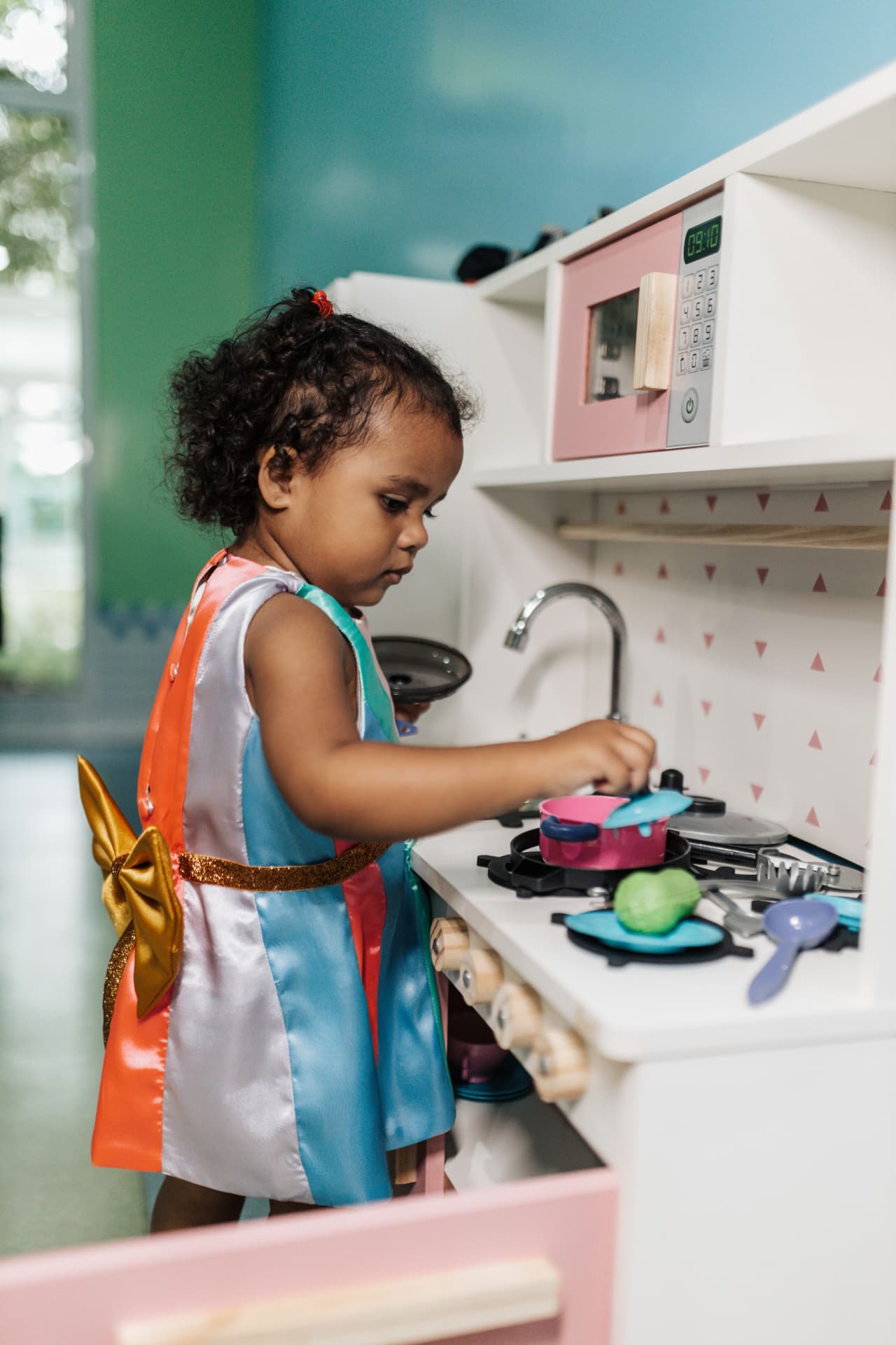 A young child playing in a toy kitchen